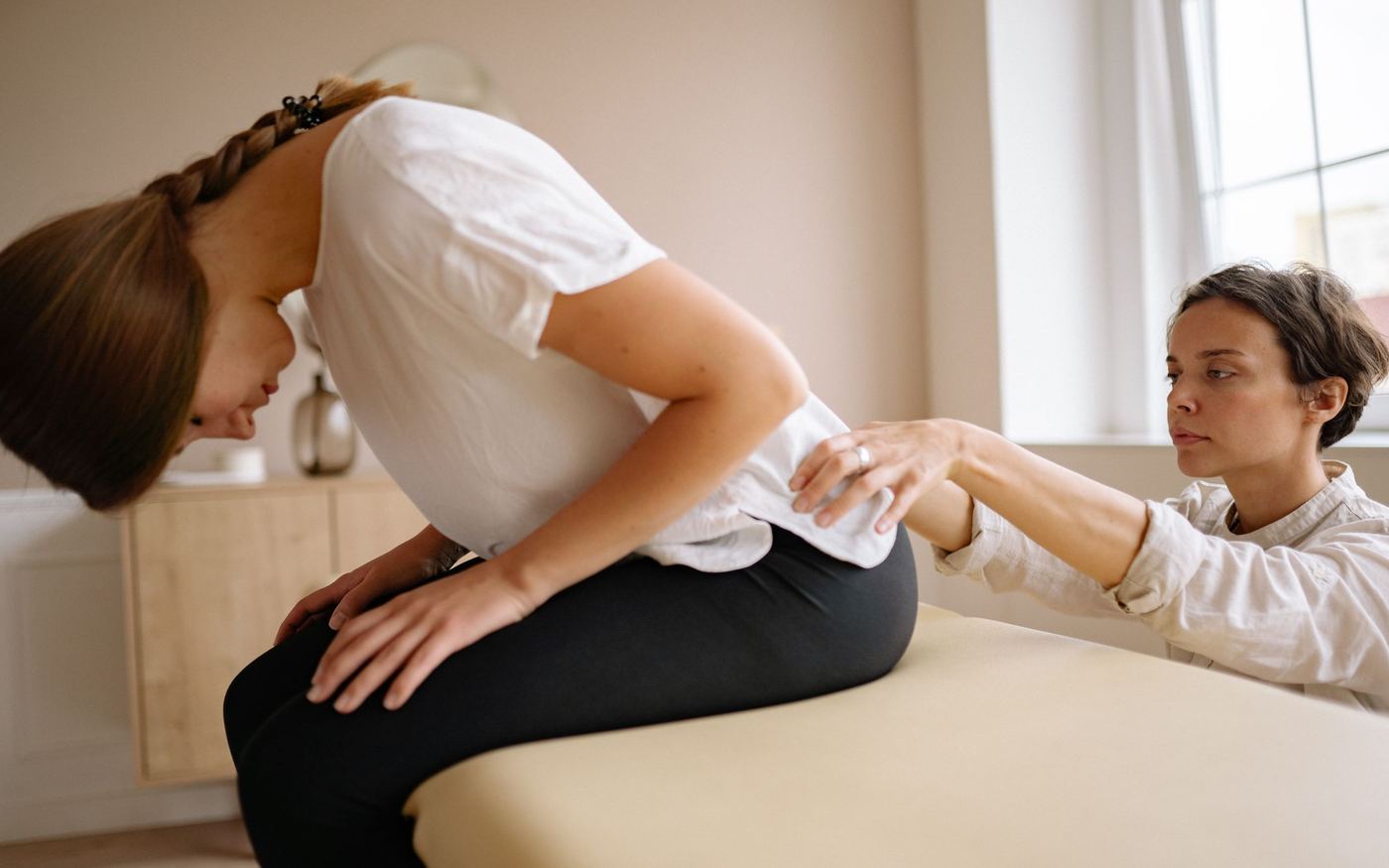Physiotherapeutin untersucht die Lendenwirbelsäule einer Patientin